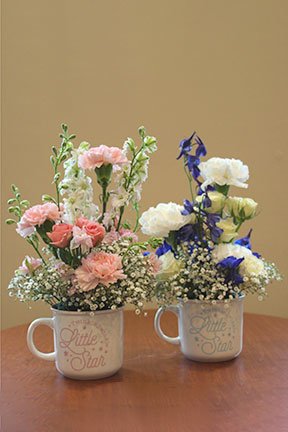pink or blue assorted flowers in mugs to congratulate for a baby