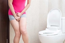 woman standing in front of a toilet needing to pee